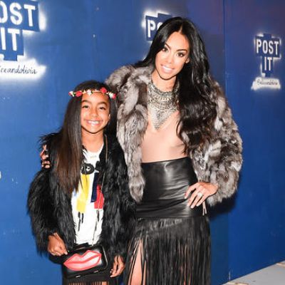 They are posing for the camera wearing a fluffy jacket and a matching black skirt.